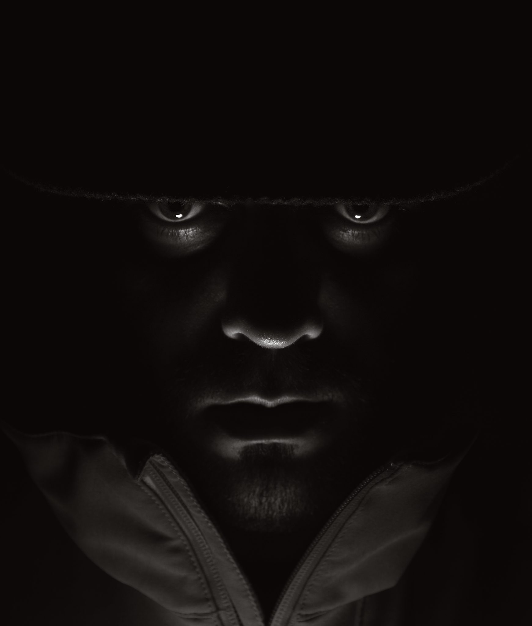 Primer plano en blanco y negro de una persona bajo un sombrero, con los ojos iluminados.