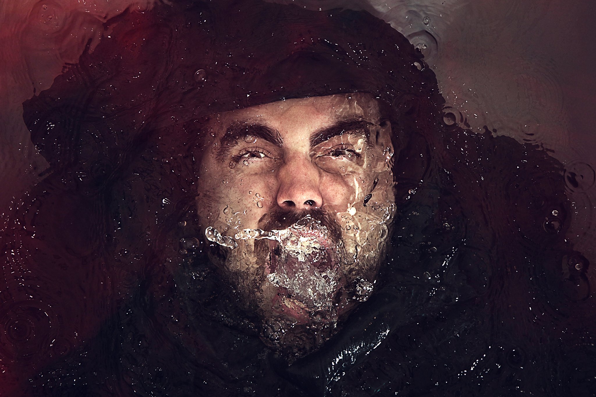 Retrato visto a través del agua, con burbujas y reflejos rojizos.