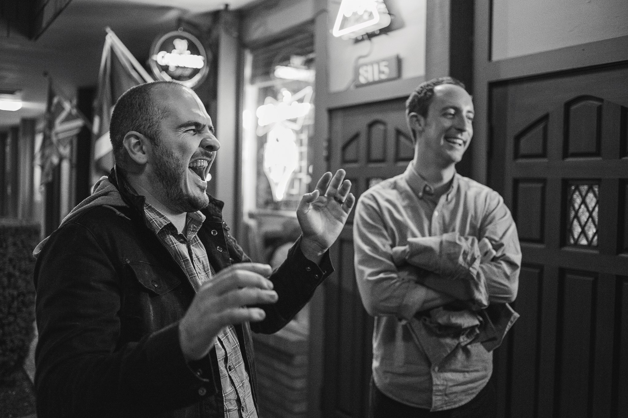Varias personas conversan y ríen dentro de un local, en blanco y negro.