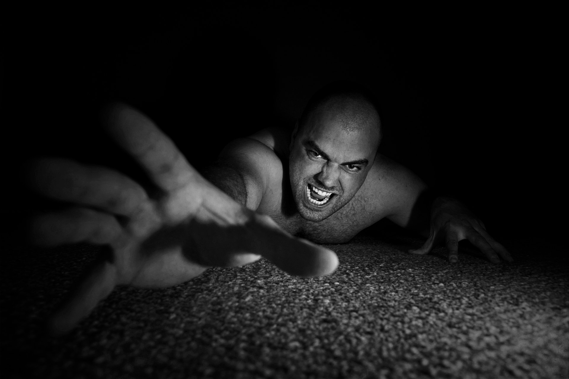 Figura en blanco y negro extendiendo una mano hacia la cámara desde el suelo.