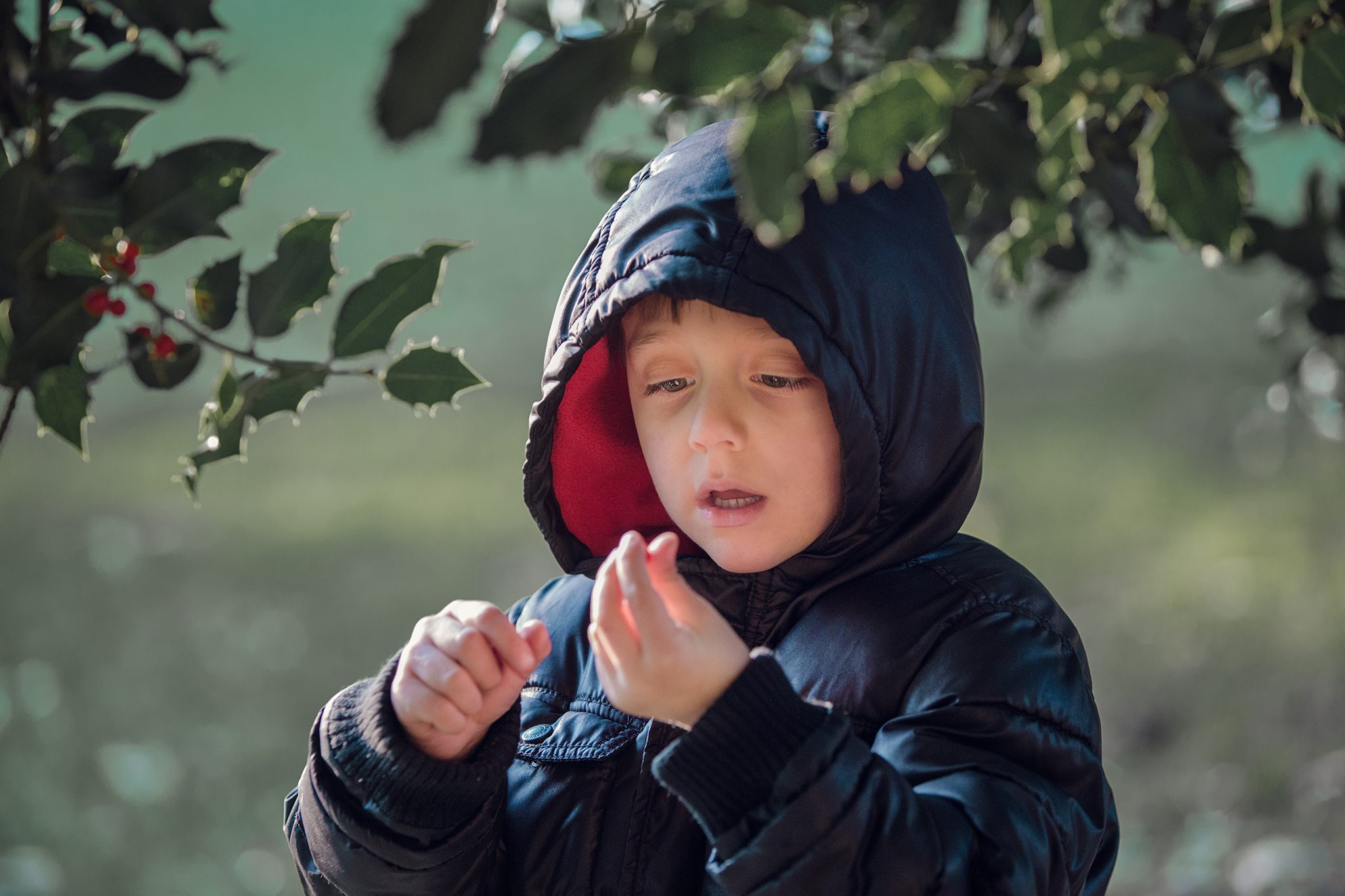 Niño con capucha azul observado durante un momento cotidiano al aire libre.