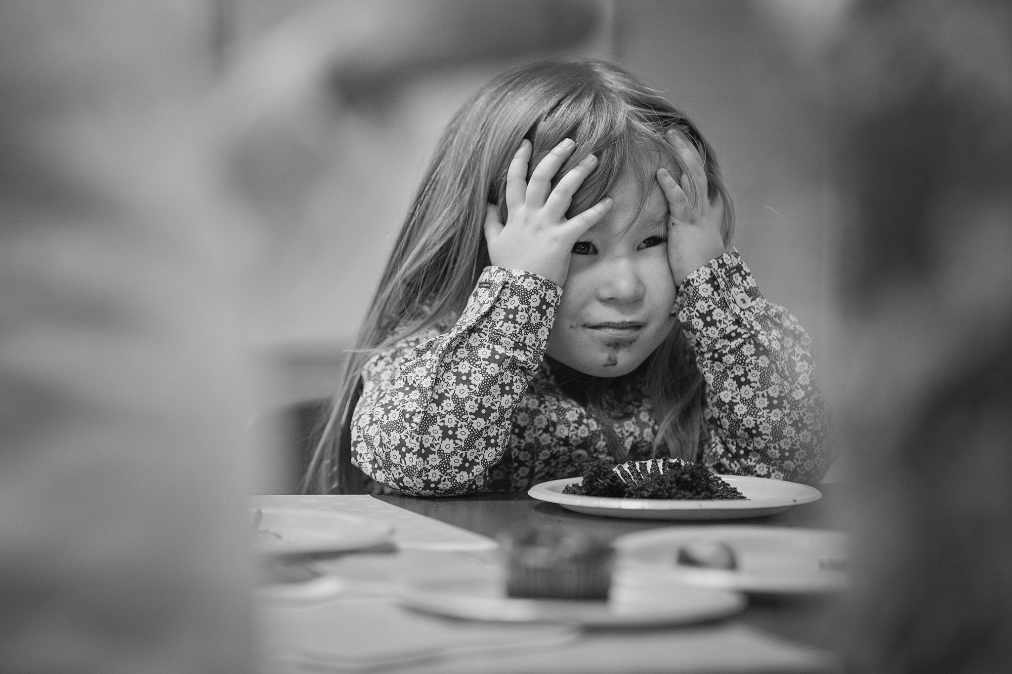 Niña con las manos sobre el rostro durante un momento cotidiano en blanco y negro.